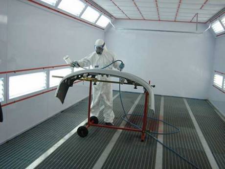 A worker is painting the components in painting workshop with steel grating floor.