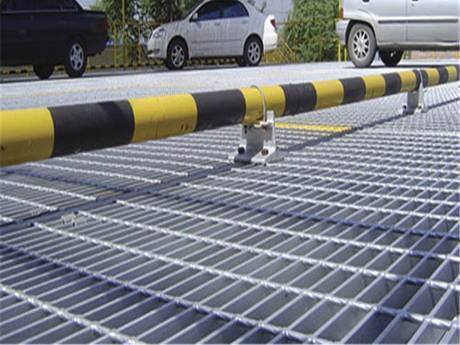 A car is parking in a open parking lot with steel grating floor.
