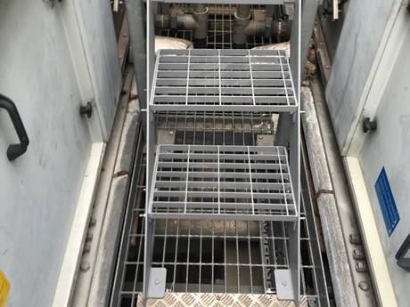 Steel grating stair tread and its both sides are concrete walls.