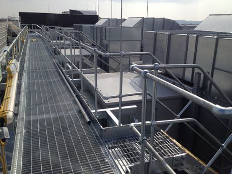 Steel grating walkway beside metal buildings roof in chemical plant.